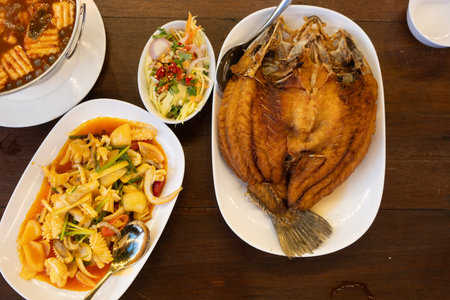 Fried sea bass with fish sauce served with stir fried squid with salted egg yolk. Delicious Thai dish.の写真素材