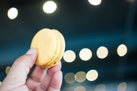 Tasty lemon macarons on hand, exuding sweet and tangy dessert perfectionの写真素材