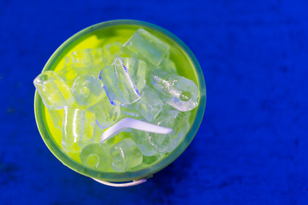Full of ice cubes in plastic bucket on blue background.の写真素材