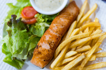 Plate of grilled salmon steak served with vegetables and french fries. Overhead viewの写真素材