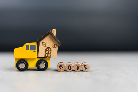 Wood car carry a wooden model home and text of MOVE. The idea of moving new homeの写真素材