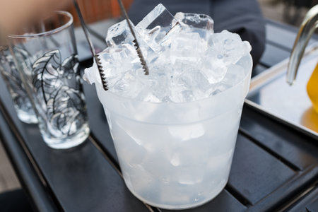Man use stainless steel tongs keep ice in to glass for drinkの写真素材