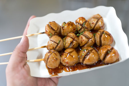 Meatball in sweet sauce in a paper plate on hand, thai food style.の写真素材