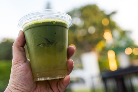 Hand holding a glass of iced green tea with lemon and lychee. Close upの写真素材