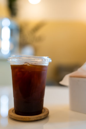 Iced americano coffee in plastic cup on table at cafeの写真素材