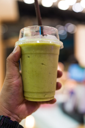Avocado smoothie in glass on hand at night market