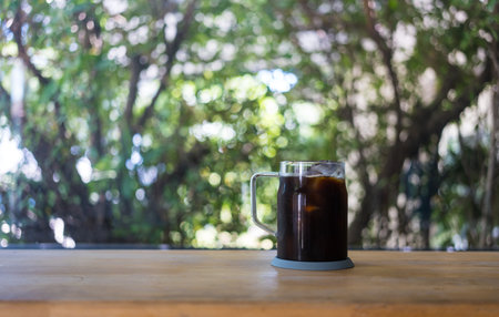A glass cup of iced black coffee americano on a wooden table in homeの写真素材