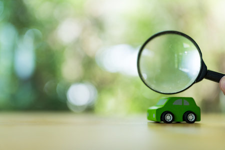 Wooden green car toy and magnifying glass is looking the car at the. Minimalism. The concept of car insurance, buying and selling cars and inspect cars conceptの写真素材