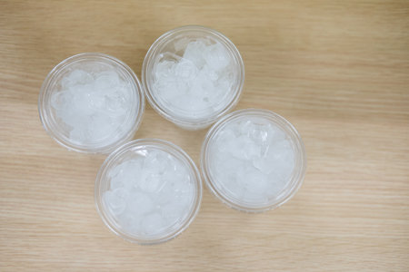 Top view of ice in a clear plastic glass on wood tableの写真素材