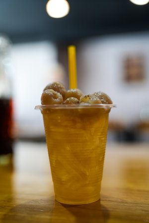 A refreshing longan drink served in a glass with ice on wood table.の写真素材