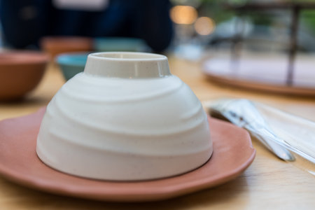 Empty upside down ceramic bowl ready to use in restaurant on wood tableの写真素材