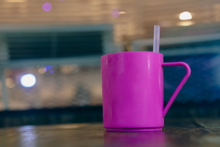 A pink cup with cold water and straw on wood tableの写真素材