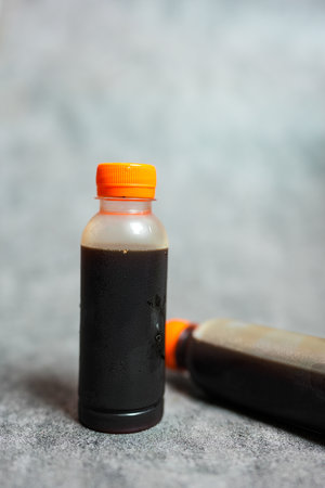 Bottle with orange lid of tasty cold brew on grey backgroundの写真素材