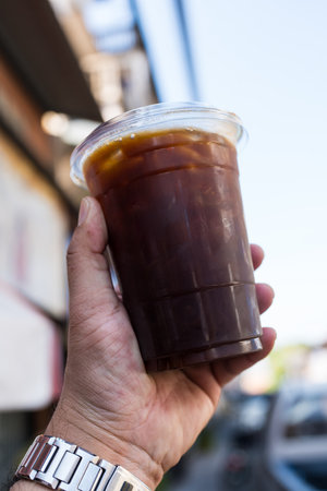 Close up of take away plastic cup of iced black coffee or Americano on handの写真素材