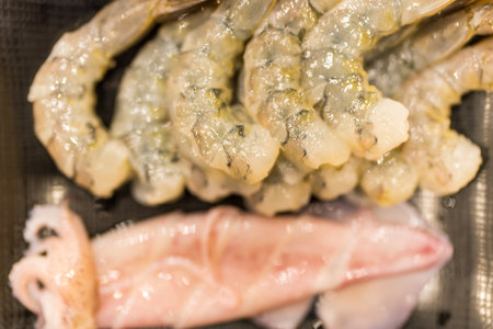 Fresh peeled raw shrimp and squid served on black tray for sukiyakiの写真素材