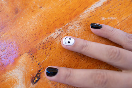 Fingernails with smiley faces black nail art featuring smiling faces on fingers. Men fingernail with black on white nail polishの写真素材