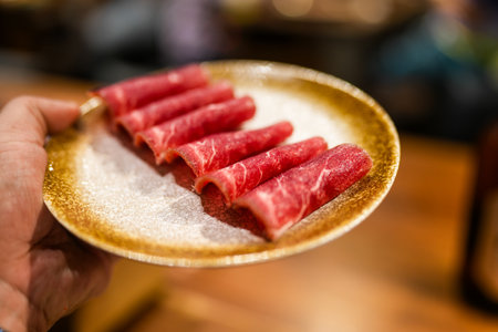 A rolled thinly sliced raw beef served on dish in hand