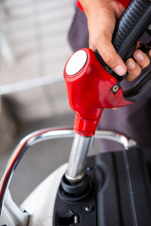 Detail of the hands of a red gas station attendant fueling a motorcycleの写真素材