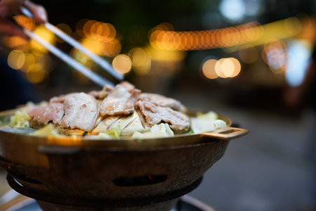 Unrecognizable man is enjoying cooking and eating Moo Ka Ta in outdoor restaurantの写真素材