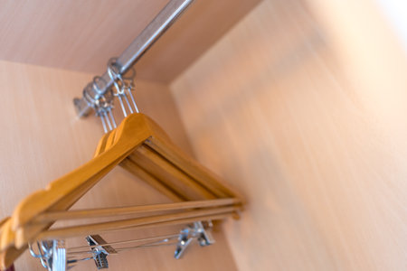 Many wooden brown hangers on a rod at hotelの写真素材