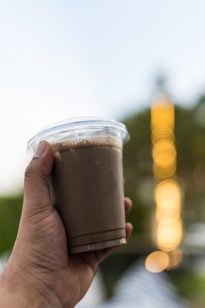 Close up view of ice cocoa drink in a plastic glass on hand manの写真素材