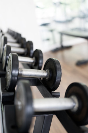 Rows of metal dumbbells on rack for strength training in gymの写真素材