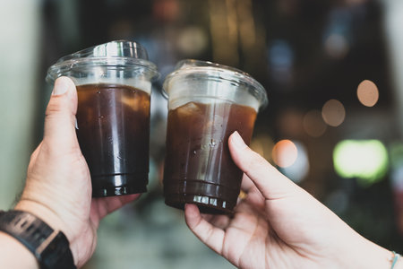 Cheers to refreshing beverages. Two hands hold iced coffee drinks, showcasing delightful. Perfect for coffee loversの写真素材