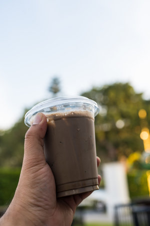 Hand holding plastic cups of ice cocoa, drink beverageの写真素材