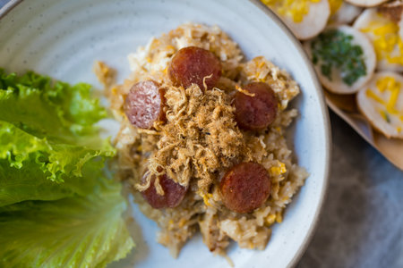 Fried rice topped with sliced chinese sausage and dried shredded pork in white bowl.の写真素材
