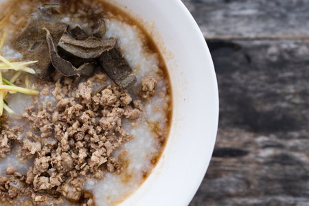Congee, pork filling, boiled pork liver, and minced pork in a bowl. Easy breakfast. Top viewの写真素材