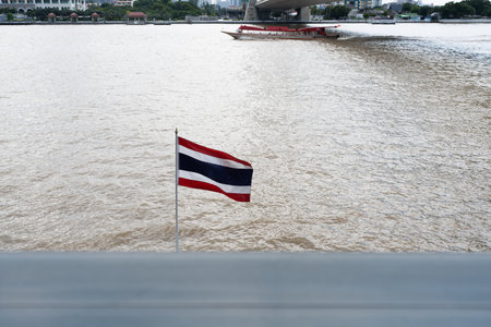 A Thailand national flag blowing by wind against chao phraya river