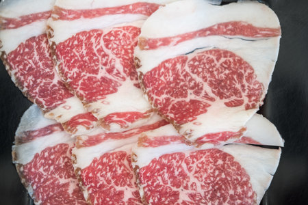 Close up shot of thinly sliced beef for sukiyaki with a high degree of marbling, showing its...