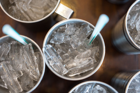 Ice in stainless cup with straw on wood table