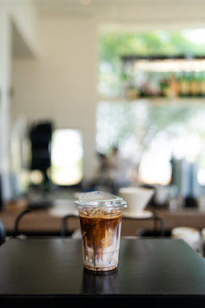 Cup of ice cafe latte with two layers, espresso and fresh milk in take away glass on table