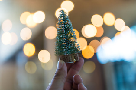 Christmas tree in a bokeh light on man handの写真素材