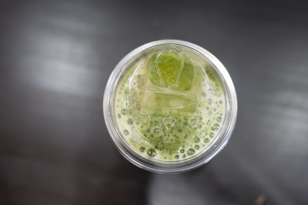 Top view of a glass filled with iced green matcha latte, a refreshing and cool beverageの写真素材