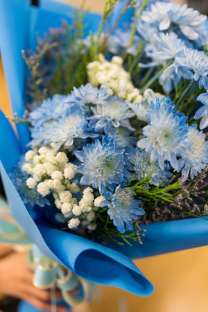 A bouquet of blue flowers with blue and white ribbon in handの写真素材
