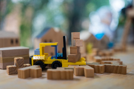 Toy yellow forklift holds a letter block and a wooden home background. Construction site home