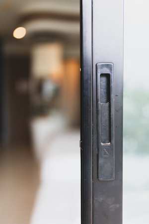 Close up view of a sliding glass door or window with a black aluminum frame. The focus is on the handles mechanisms of the door.の写真素材