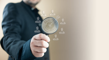 Talent Search and Recruitment Concept. Hand holding magnifying glass over candidate icons, symbolizing talent acquisition, recruitment and employee selection process.の写真素材