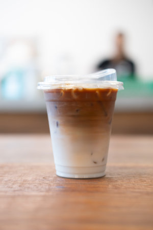 Take home cup iced latte coffee on wood tableの写真素材