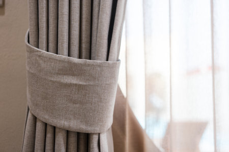 Close up of fabric strap on elegant gray curtain tied with soft natural lightingの写真素材