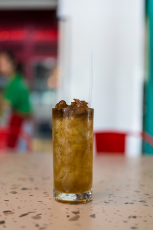 Refreshing tropical juice with ice in a clear glass sits on table