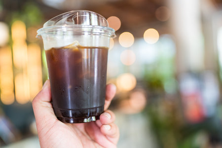 Man hand raised and holding up iced drink in the coffee shop