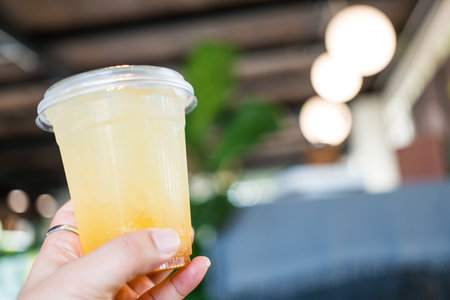 Human hand raised and holding up iced lemon teaの写真素材