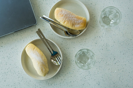 Top view of two long roll filled with white cream with powdered sugar at coffe shop.