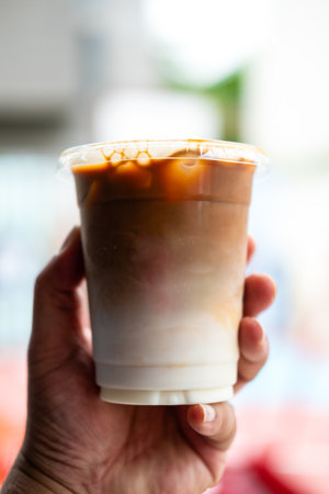 A glass is filled with cold latte drink with fresh milk on handの写真素材