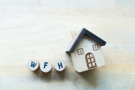 WFH cubes wooden Lined up into text on the wood desktop with a home model. The concept of work at home. Focus on wooden blocksの写真素材
