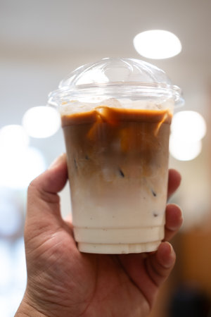 Someone holding a cup of iced cafe latte with two layer, espresso and fresh milkの写真素材