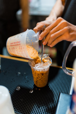Barista pour Thai tea into ice make Thai milk tea at coffee shop.の写真素材